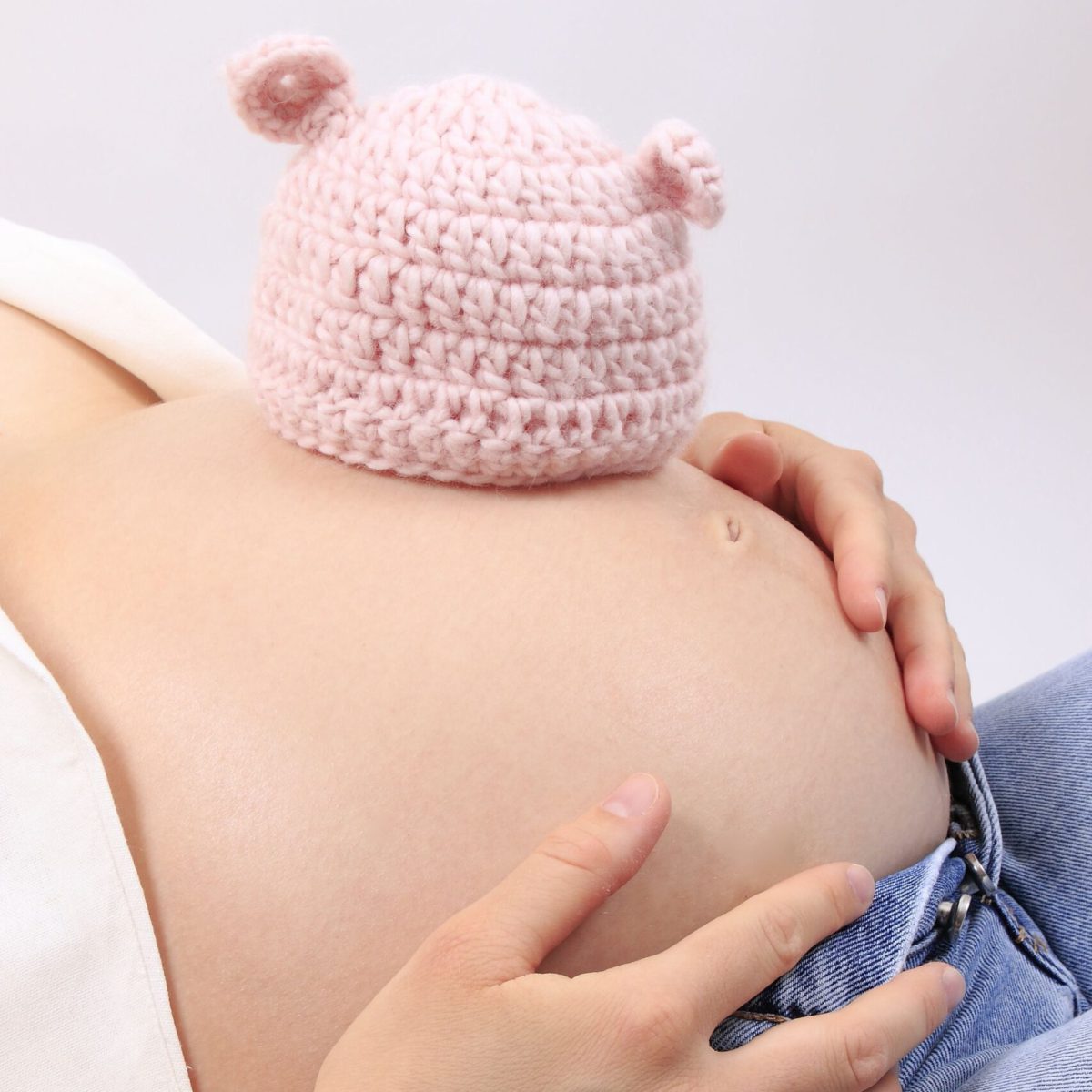 Gehäkelte Babymütze auf schwangerem Bauch